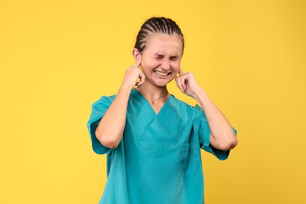 Vista frontal doctora en camisa médica cubriendo sus oídos, emoción de salud de virus covid-19 hospital de enfermería de color