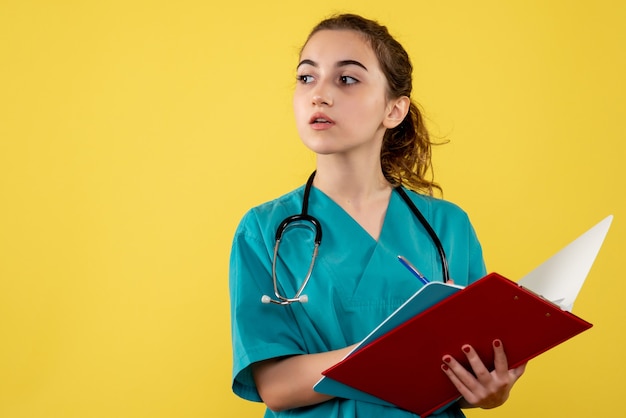 Vista frontal de la doctora en camisa médica escribiendo notas en la pared amarilla