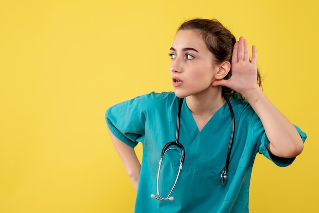 Foto gratuita vista frontal doctora en camisa médica escuchando, color virus pandémico covid-19 uniforme emoción salud