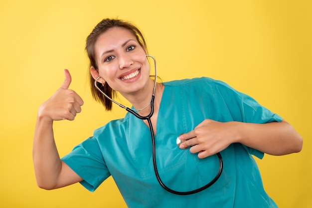 Foto gratuita vista frontal doctora en camisa médica con estetoscopio sobre fondo amarillo