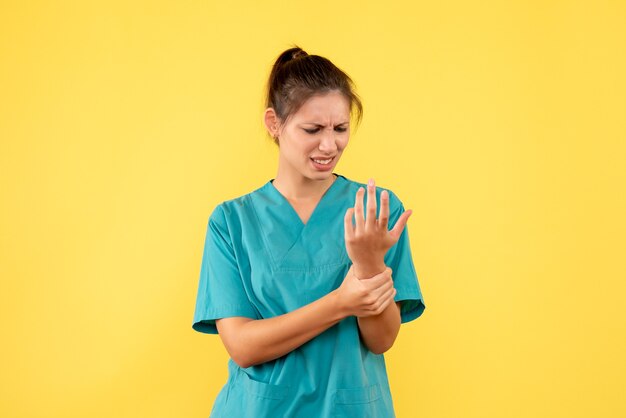 Vista frontal doctora en camisa médica se lastimó el brazo sobre fondo amarillo