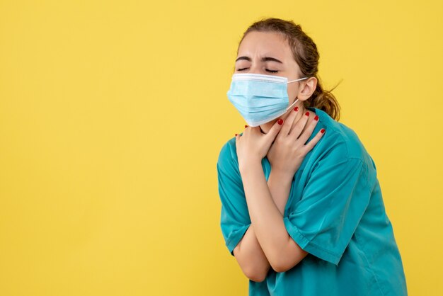 Vista frontal doctora en camisa médica y máscara con dolor de garganta, uniforme de color covid-19 del virus de la salud pandémica