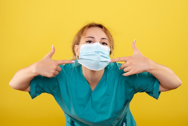 Vista frontal doctora en camisa médica y máscara estéril, color de hospital covid-19 salud emoción