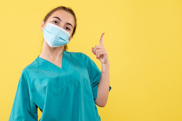 Vista frontal doctora con camisa médica y máscara estéril, salud pandémica del virus covid-19 uniforme del coronavirus