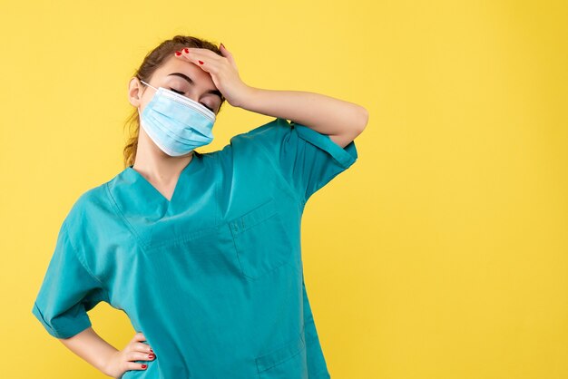 Vista frontal doctora en camisa médica y máscara estéril, uniforme de salud de color pandémico virus covid-19