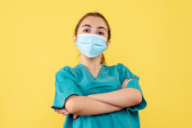 Vista frontal doctora en camisa médica y máscara estéril, uniforme de salud de color pandémico virus covid-19