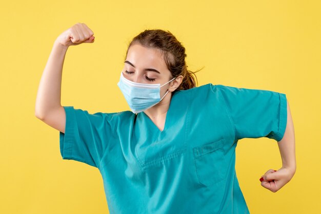 Vista frontal doctora en camisa médica y máscara estéril, uniforme de salud de color virus covid-19