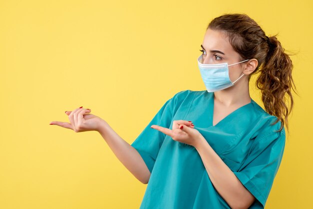 Vista frontal doctora en camisa médica y máscara estéril, uniforme de salud de color virus covid-19