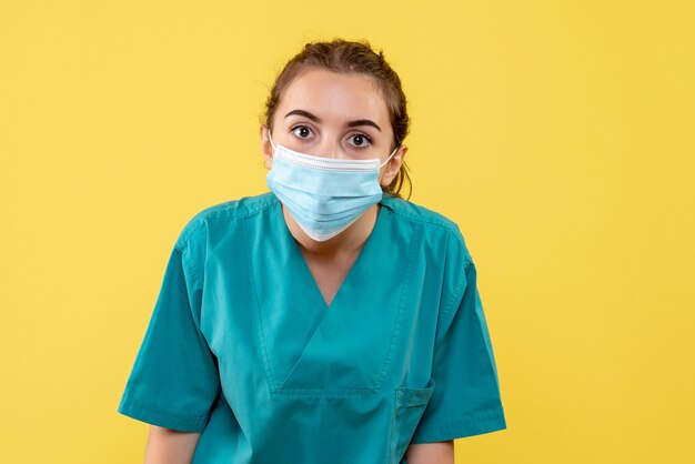 Vista frontal doctora en camisa médica y máscara estéril, uniforme de virus covid-19 de salud de color pandémico