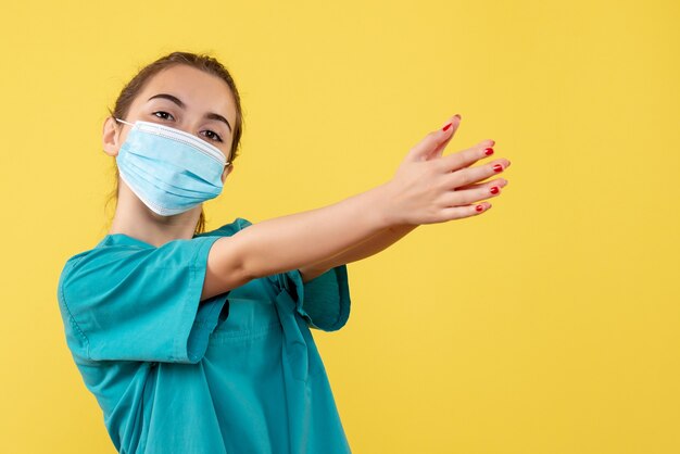 Vista frontal doctora en camisa médica y máscara estéril, uniforme de virus covid-19 de salud de color pandémico