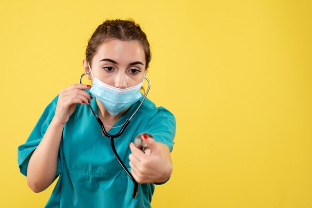 Vista frontal doctora en camisa médica y máscara con estetoscopio, virus color uniforme emociones covid-19 salud