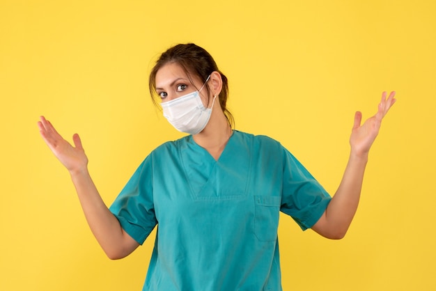 Vista frontal doctora en camisa médica y máscara sobre fondo amarillo