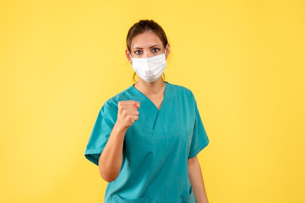 Vista frontal doctora en camisa médica y máscara sobre fondo amarillo