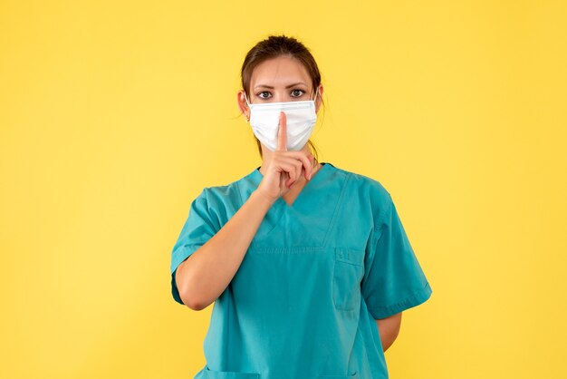 Vista frontal doctora en camisa médica y máscara sobre fondo amarillo