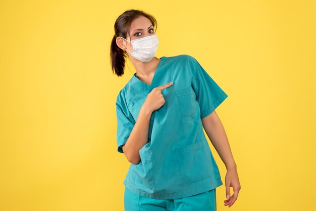 Vista frontal doctora en camisa médica y máscara sobre fondo amarillo