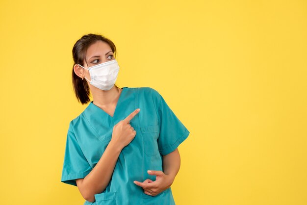 Vista frontal doctora en camisa médica y máscara sobre fondo amarillo