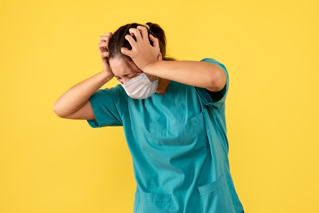 Vista frontal doctora en camisa médica y máscara sobre fondo amarillo