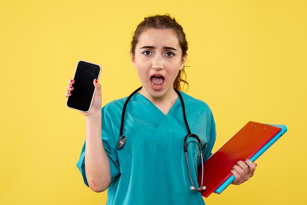Vista frontal doctora en camisa médica con notas y teléfono, pandemia de virus salud emoción uniforme covid-19