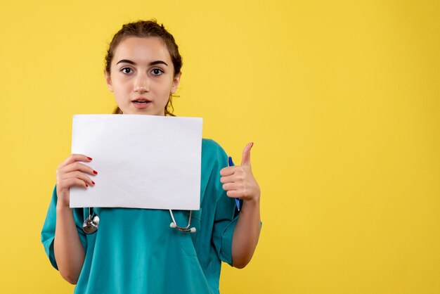 Vista frontal doctora en camisa médica con papeles y estetoscopio, virus uniforme salud pandémica covid-19 emoción