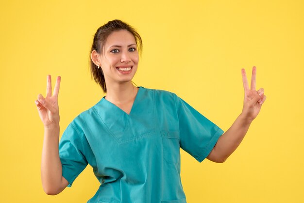 Vista frontal doctora en camisa médica sobre fondo amarillo