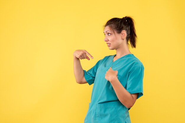 Vista frontal doctora en camisa médica sobre fondo amarillo