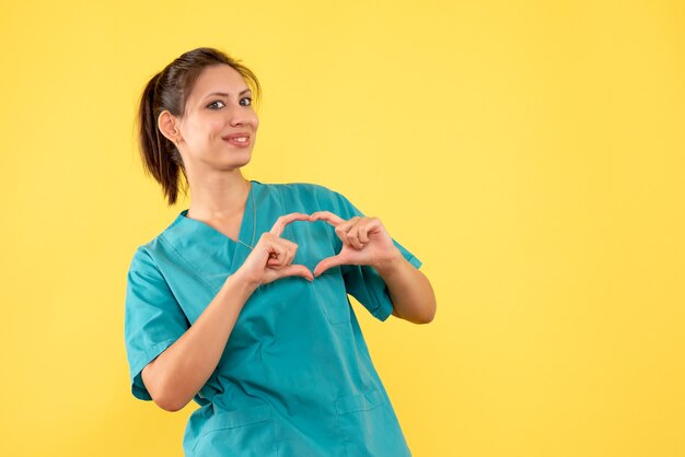 Vista frontal doctora en camisa médica sobre fondo amarillo