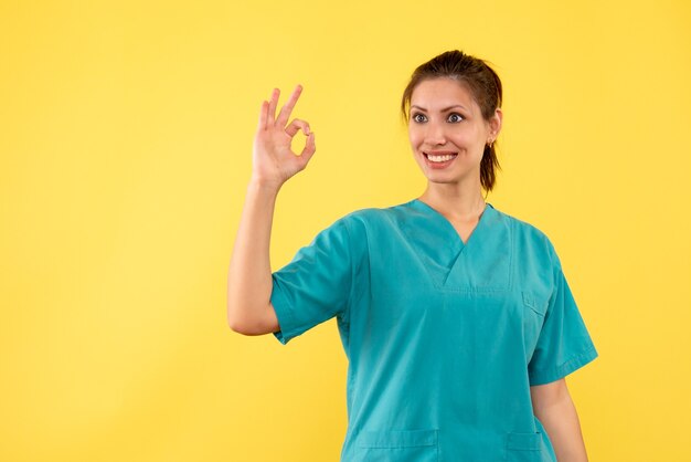 Vista frontal doctora en camisa médica sobre fondo amarillo