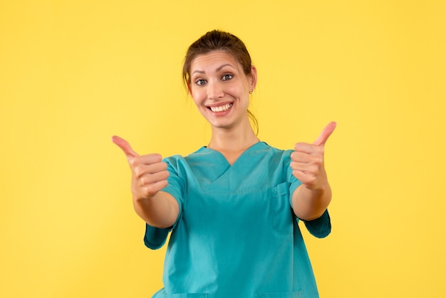 Vista frontal doctora en camisa médica sobre fondo amarillo