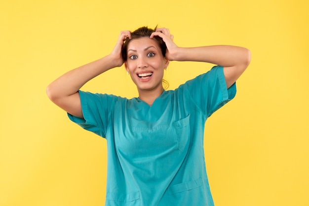 Vista frontal doctora en camisa médica sobre fondo amarillo