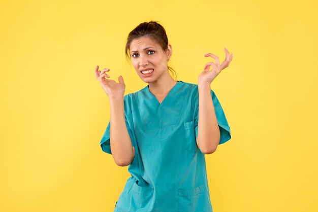 Vista frontal doctora en camisa médica sobre fondo amarillo