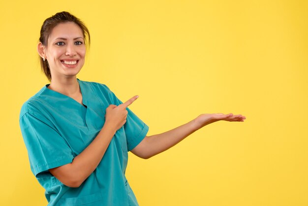 Vista frontal doctora en camisa médica sobre fondo amarillo