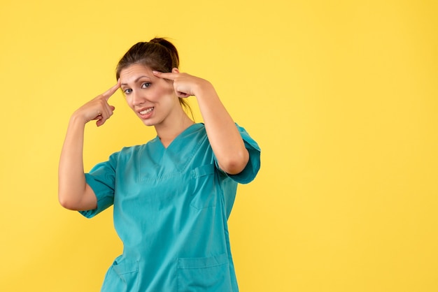 Vista frontal doctora en camisa médica sobre fondo amarillo