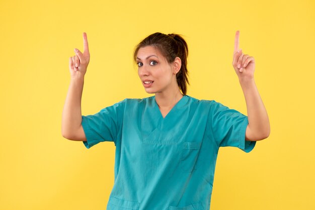 Vista frontal doctora en camisa médica sobre fondo amarillo