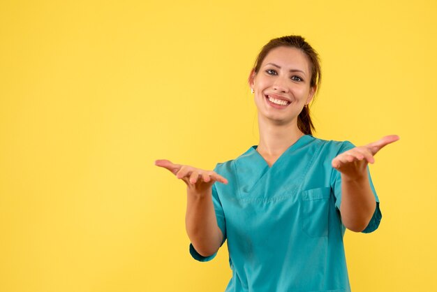 Vista frontal doctora en camisa médica sobre fondo amarillo