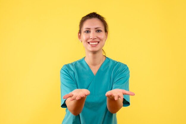 Vista frontal doctora en camisa médica sobre fondo amarillo