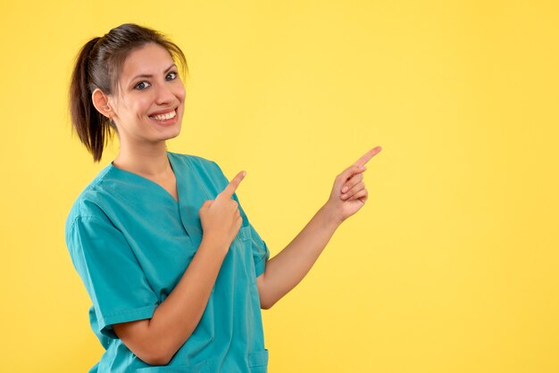 Vista frontal doctora en camisa médica sobre fondo amarillo