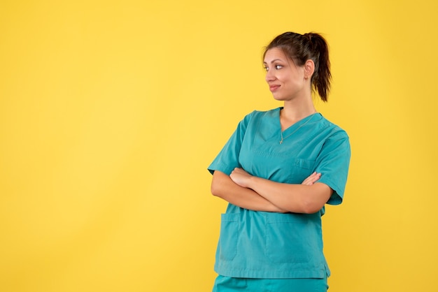 Vista frontal doctora en camisa médica sobre fondo amarillo