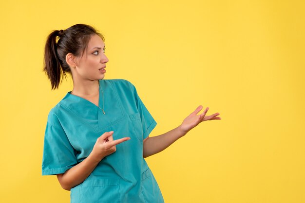 Vista frontal doctora en camisa médica sobre fondo amarillo