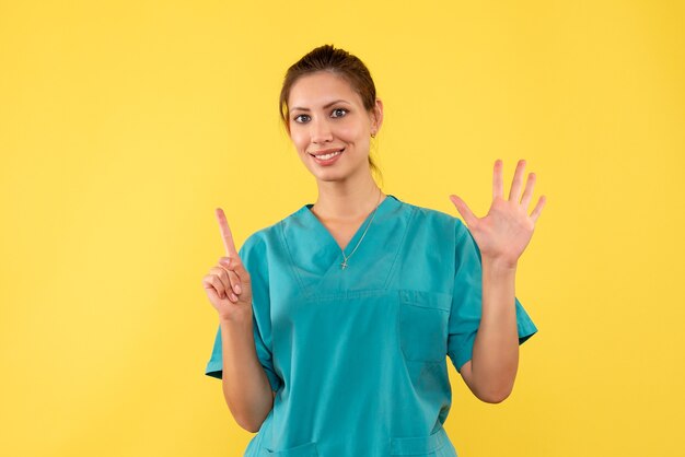 Vista frontal doctora en camisa médica sobre fondo amarillo