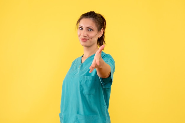 Vista frontal doctora en camisa médica sobre fondo amarillo