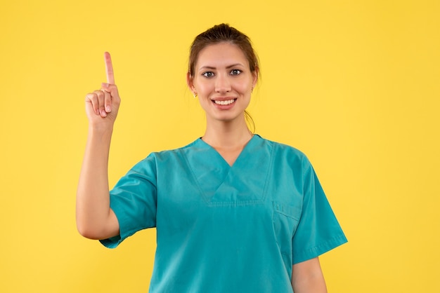 Vista frontal doctora en camisa médica sobre fondo amarillo