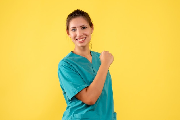 Vista frontal doctora en camisa médica sobre fondo amarillo