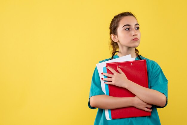 Vista frontal doctora en camisa médica sosteniendo diferentes notas, color uniforme de covid-19 de emoción de salud de virus pandémico