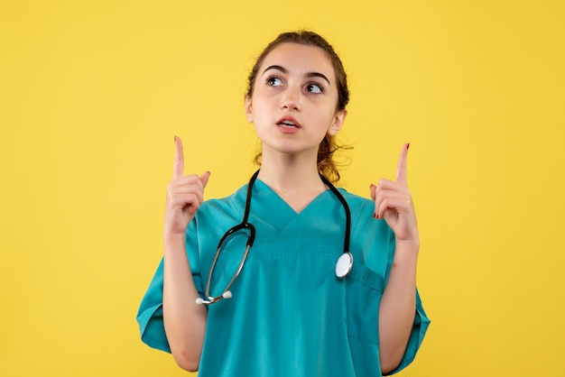 Vista frontal doctora en camisa médica, uniforme de emoción de salud de virus covid-19 de color