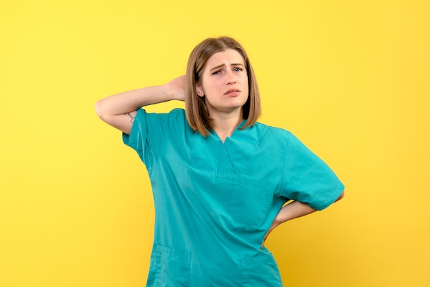 Vista frontal doctora con cara confundida en espacio amarillo