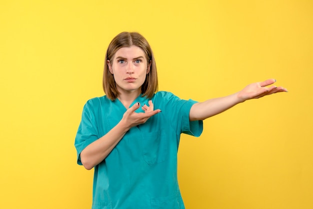 Vista frontal doctora con cara confundida en espacio amarillo