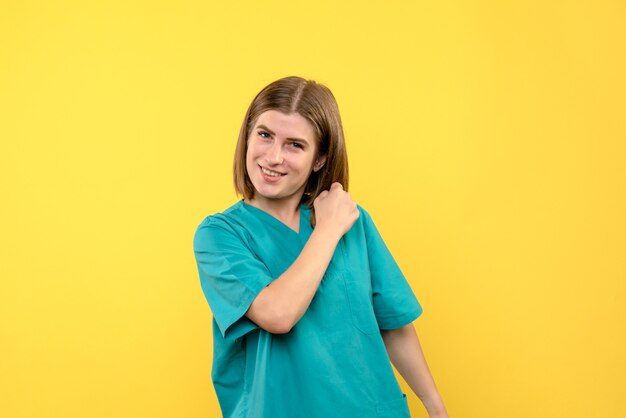 Vista frontal de la doctora con cara emocionada en pared amarilla