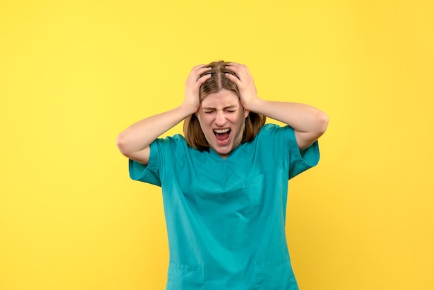 Vista frontal de la doctora con cara gritando en la pared amarilla