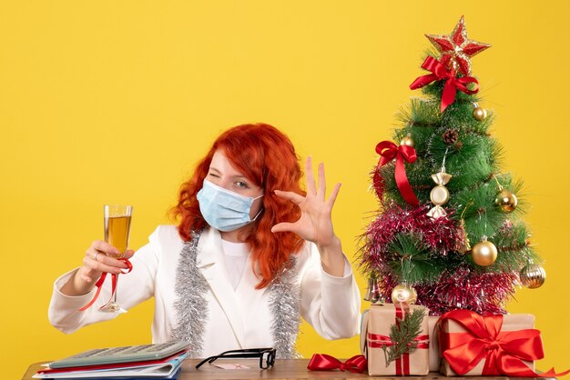 Vista frontal doctora celebrando la Navidad con copa de champán