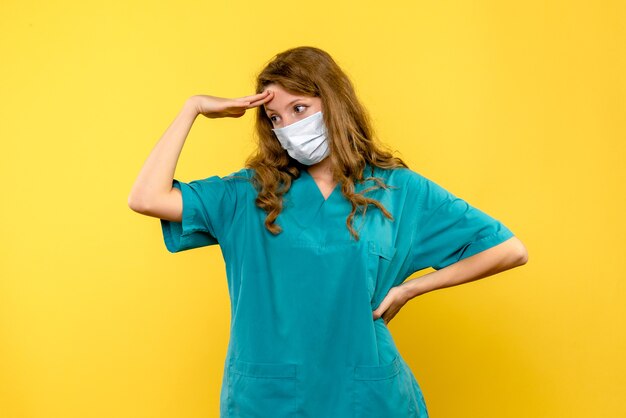 Vista frontal de la doctora destacó en máscara en pared amarilla